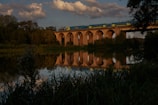 A train crossing a bridge over a calm river reflecting the sky.