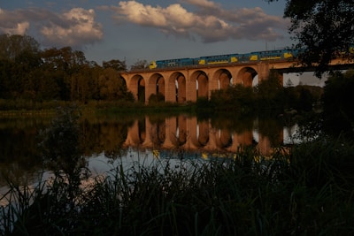 A train crossing a bridge over a calm river reflecting the sky.
