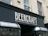 A storefront sign with the text 'BeerCraft of Bath' displayed in bold letters on a dark facade. The building is light-colored stone with two windows above the sign and a security camera mounted beside one window.