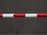 A horizontal barrier arm with red and white stripes is positioned across a flat, dark gray concrete surface.