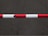A horizontal barrier arm with red and white stripes is positioned across a flat, dark gray concrete surface.
