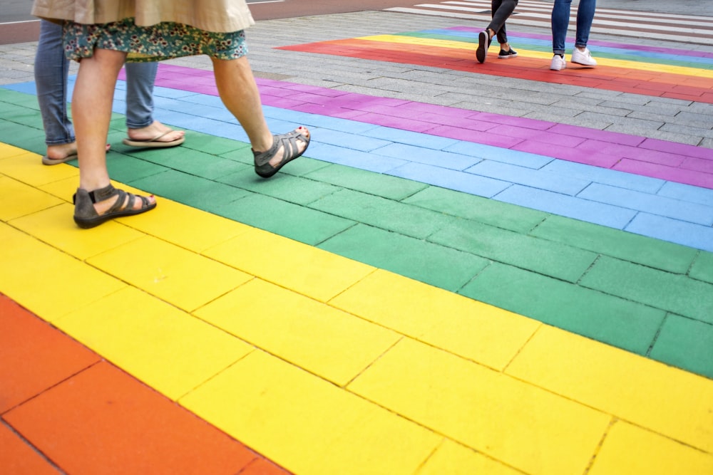 Cuatro personas caminando sobre pavimento de rayas multicolores