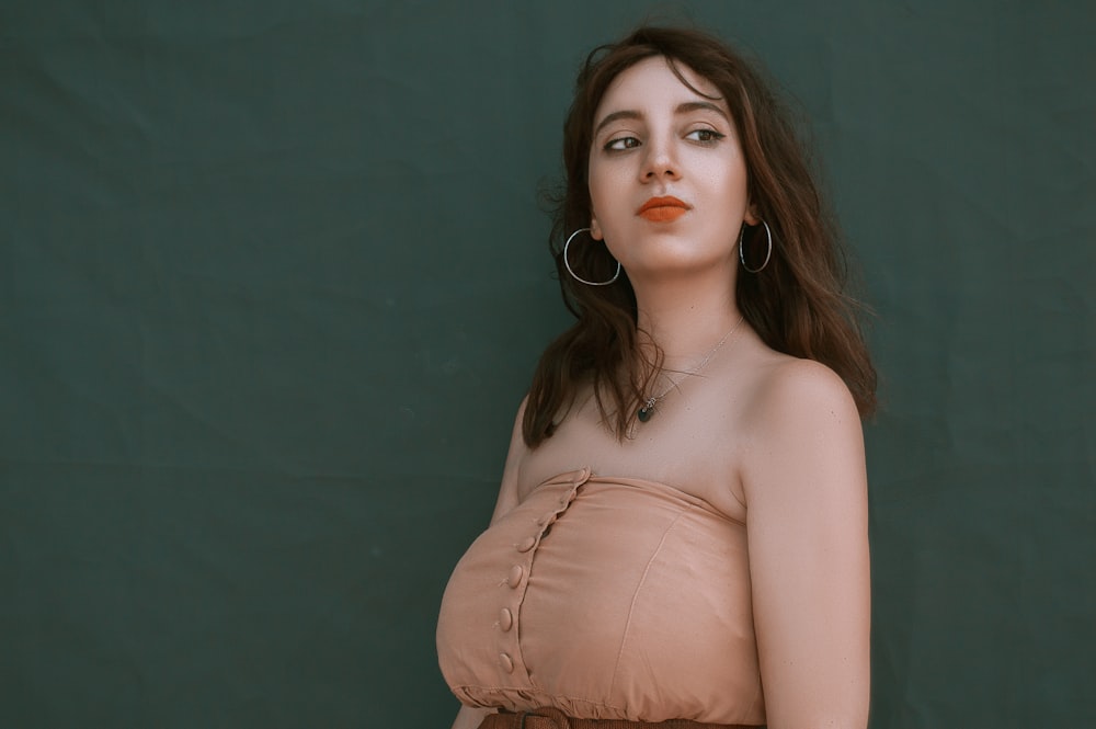 woman in brown top beside wall