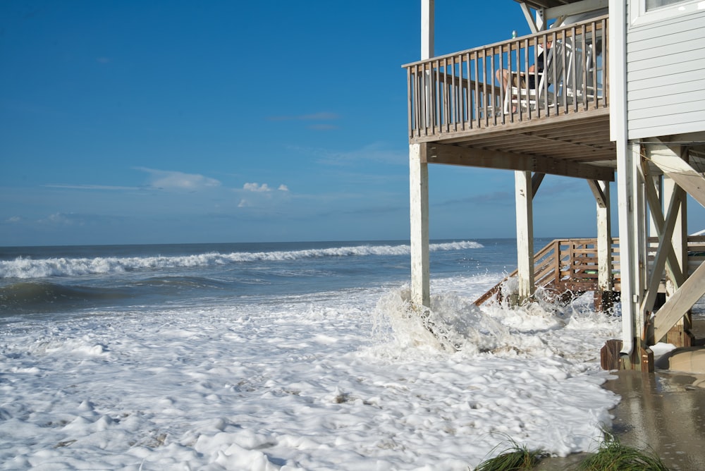 a house on a beach with waves crashing in front of it