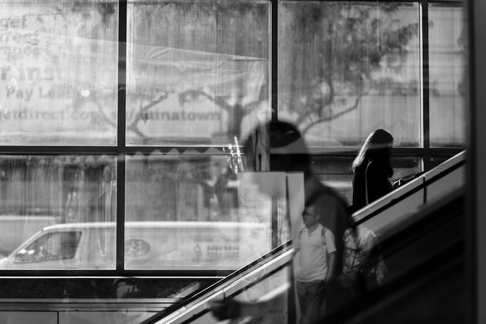 grayscale photo of woman using escalator