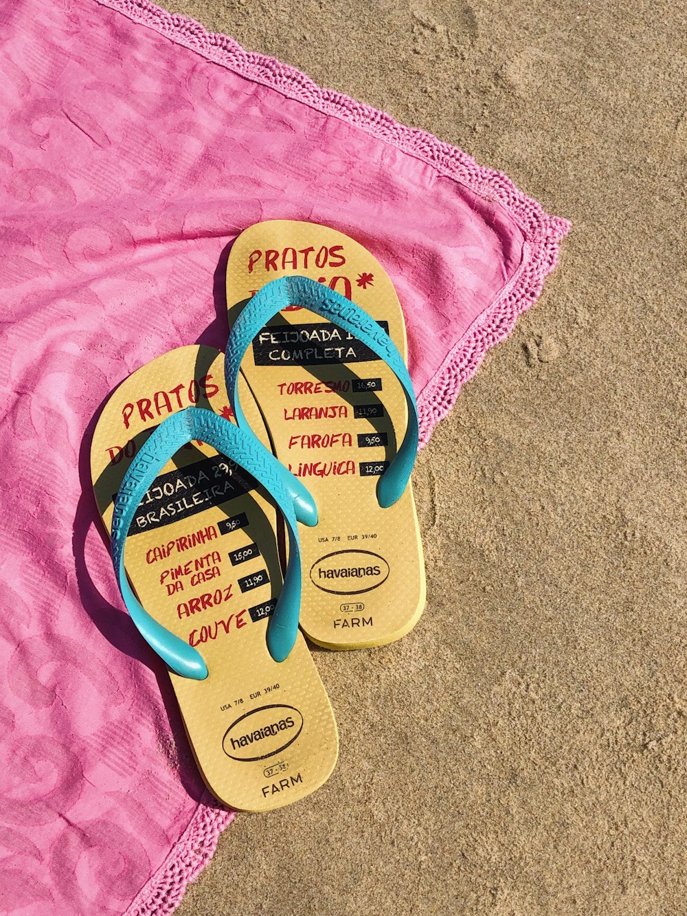 pair of yellow-and-blue havaianas flip-flops on pink textile