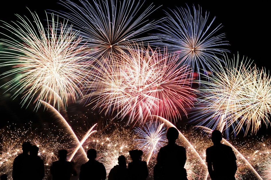 Feu d'artifice du 14 Juillet illuminant le ciel nocturne devant la foule