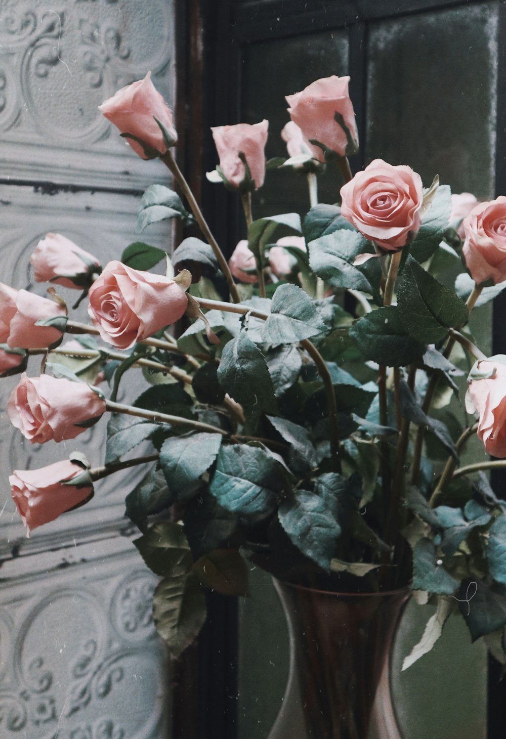 pink rose arrangement beside wall