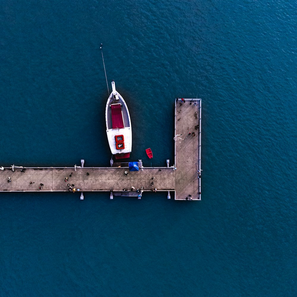 weißes und rotes Boot in der Nähe des Docks