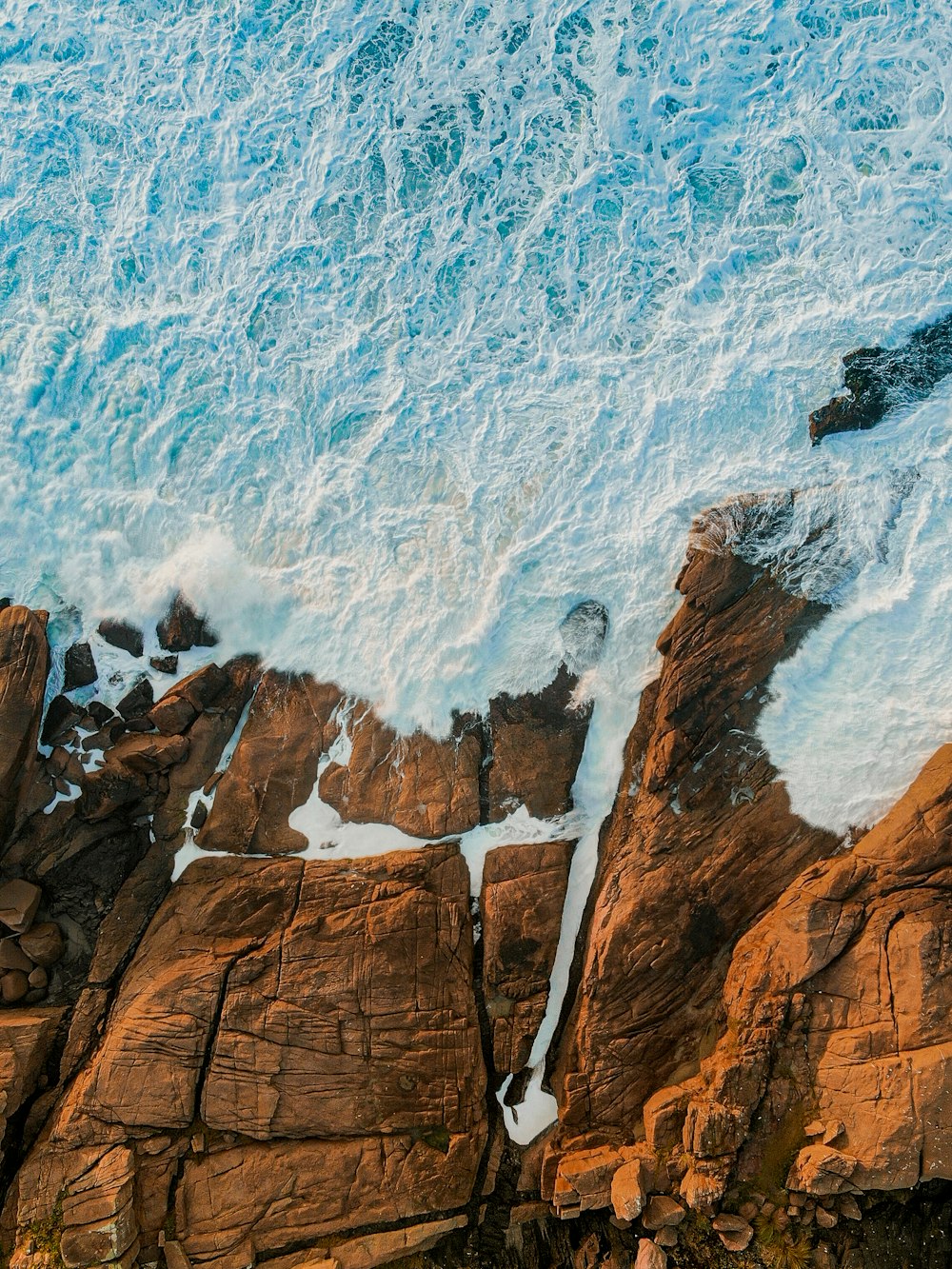 an aerial view of the ocean and rocks