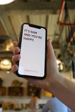 A cheerful person holding a smartphone, typing a message about their fitness journey.