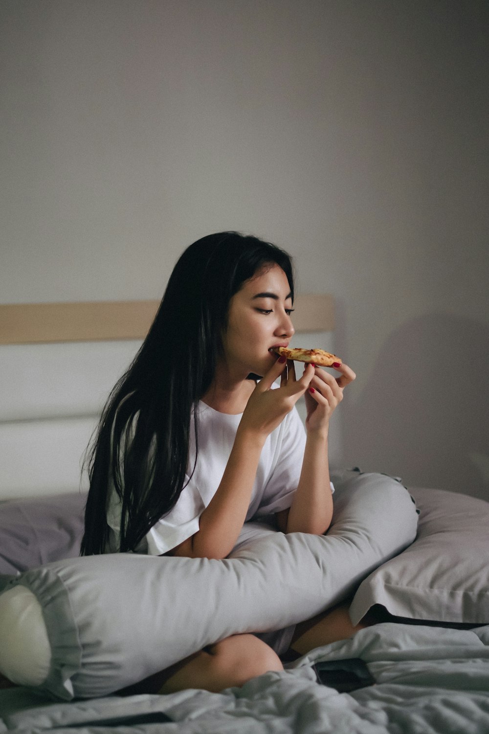 donna seduta a letto che mangia pasticcini