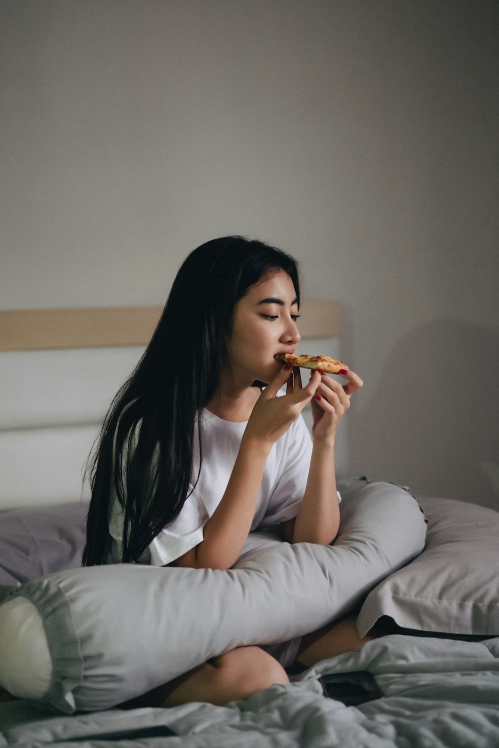 mujer sentada en la cama comiendo pasteles