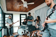 A group of musicians playing acoustic instruments together in a cozy studio space.