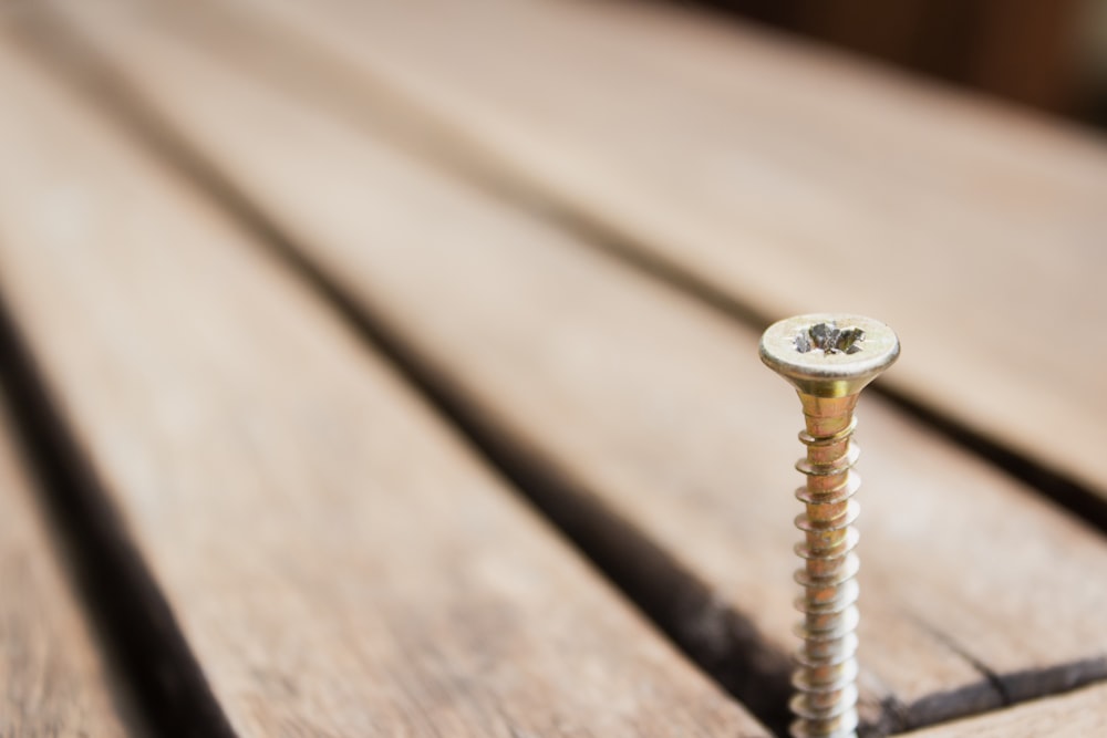 gray bolt on brown wooden plank