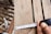 Close-up of a construction worker measuring wooden beams on a building site.