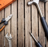 Hand tools such as wrenches and screwdrivers laid out on a wooden surface.