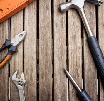 A neatly arranged set of household screwdrivers and pliers on a wooden workbench.