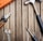 A collection of hand tools arranged on a wooden surface, including a hammer with a black handle, pliers with orange grips, an adjustable wrench, and a screwdriver.