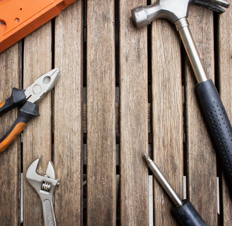 A collection of hand tools laid out on a wooden table, ready for a weekend project.