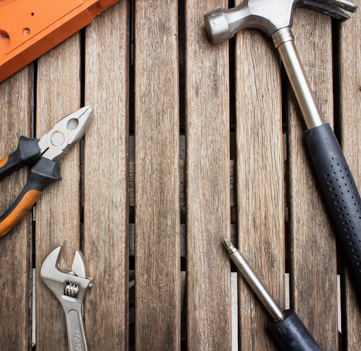 A close-up of sturdy hand tools like hammers and screwdrivers neatly arranged on a wooden workbench.
