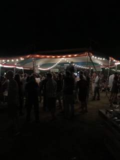 Guests enjoying a lively outdoor catering event under string lights.