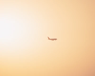 A small aircraft soaring gracefully above a golden sunrise, with the runway fading into the distance below.