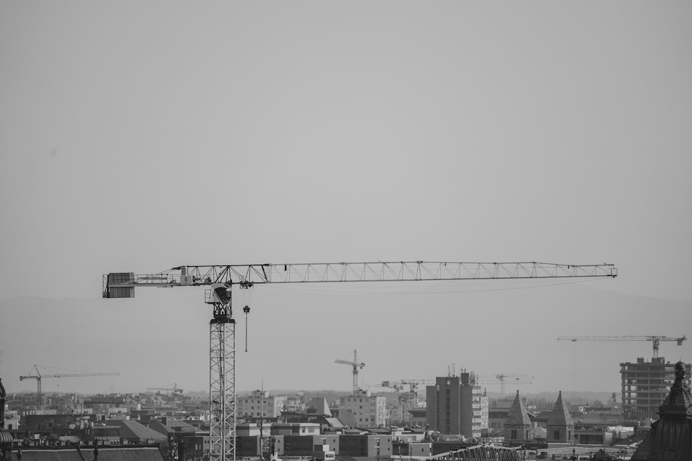 a black and white photo of a crane in a city