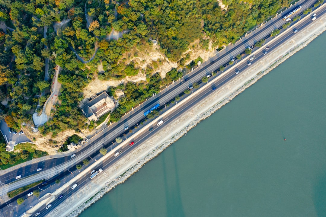 aerial photography of highway between body of water and mountain during daytime