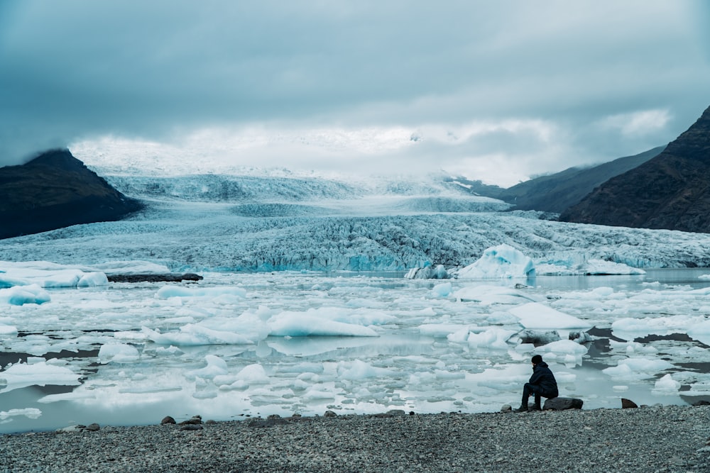 man standing on rock near glaciers