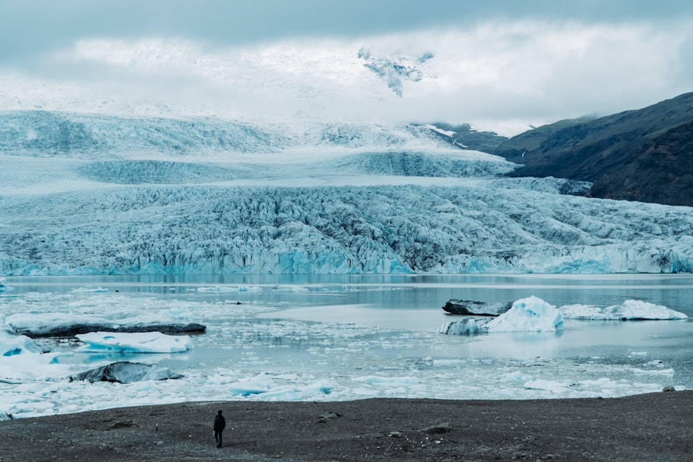 person standing beside snowy plains and frozen lake