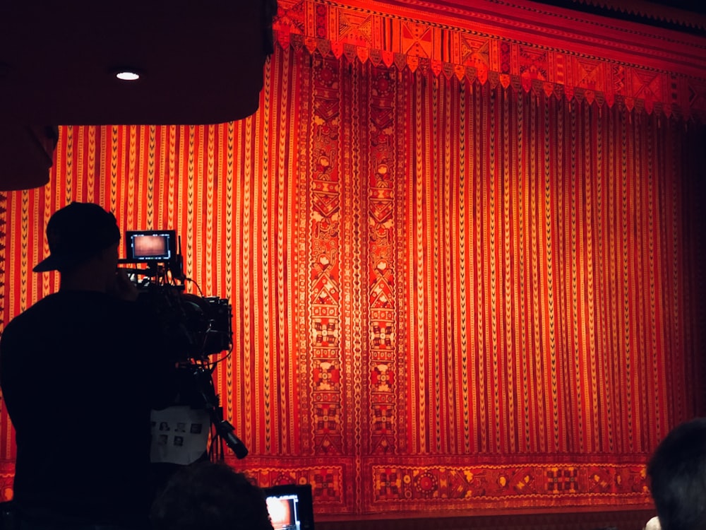 man filming red curtain