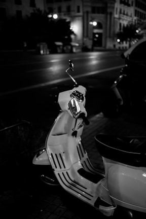 A glossy Royal Electra electric scooter parked against a modern cityscape at dusk.