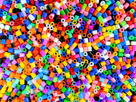 Close-up of colorful plastic pellets spilling from a container in a factory setting