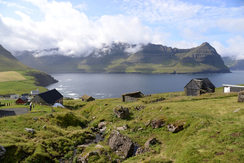 green houses near calm water and mountain