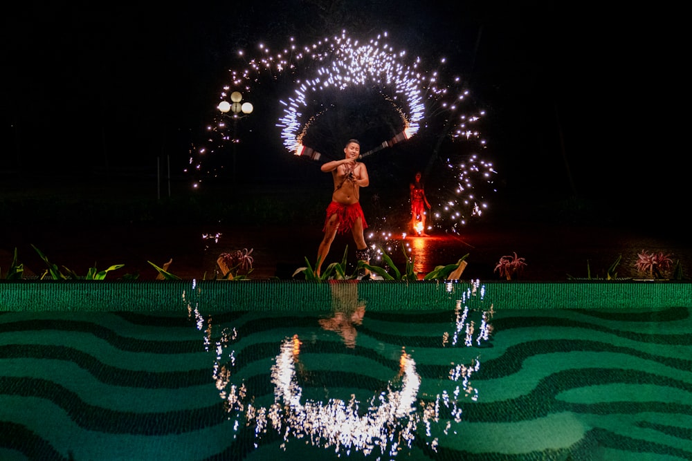 Mann Feuer tanzt neben Gewässer