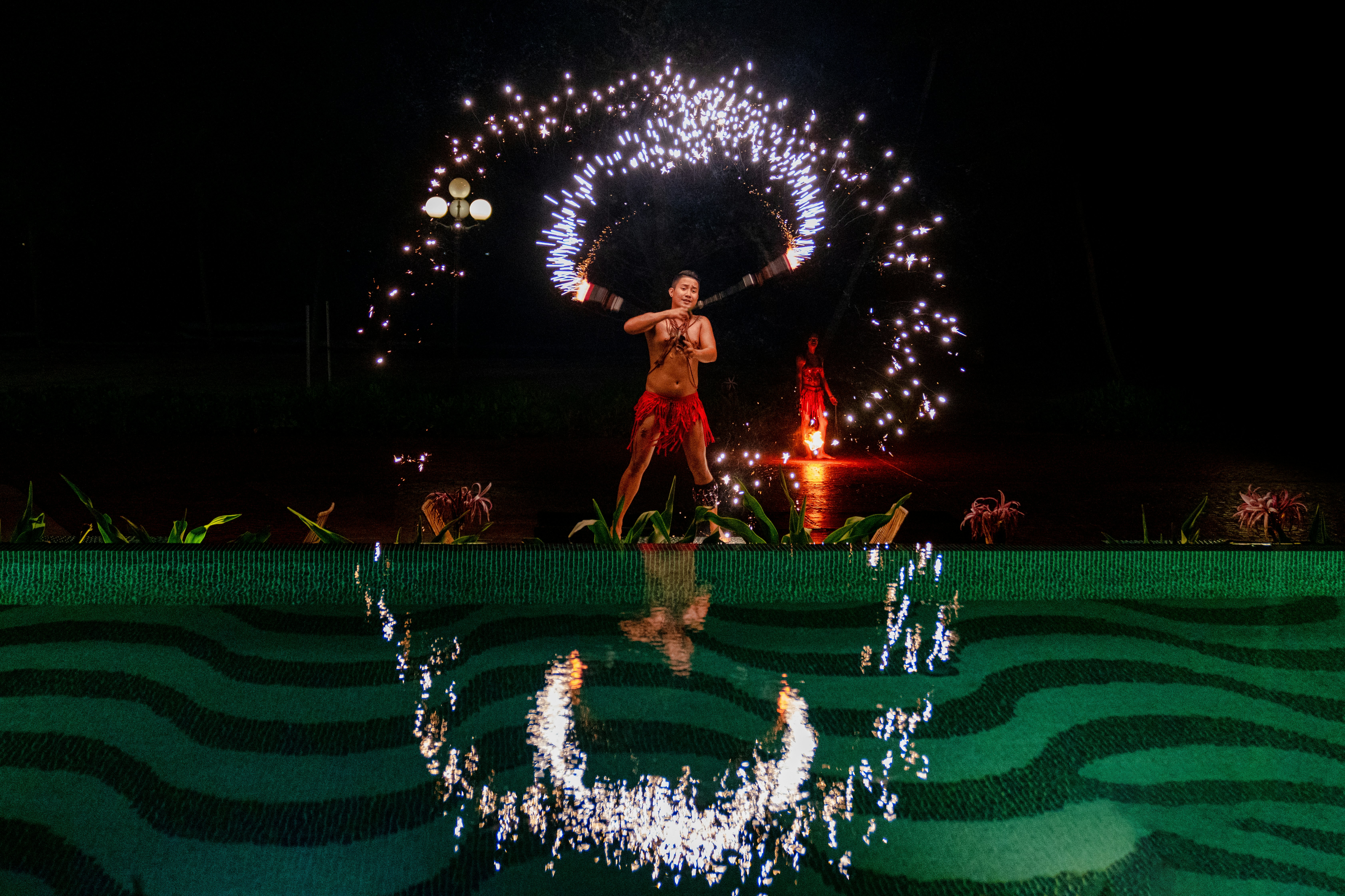 man fire dancing beside body of water