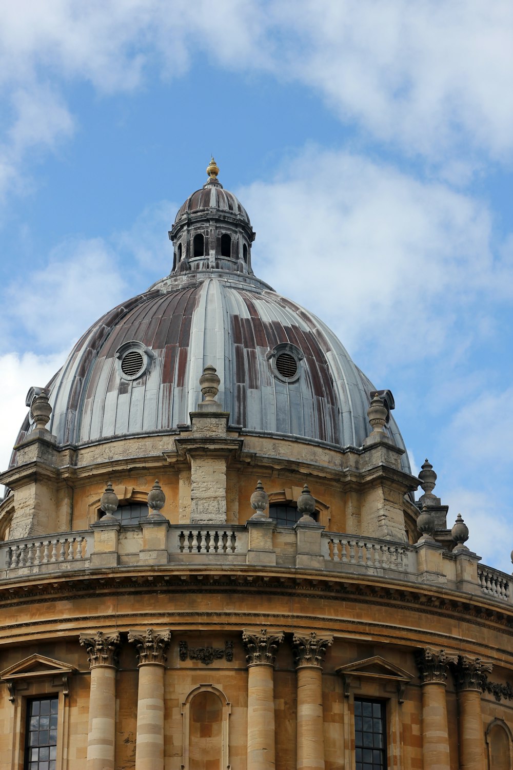 brown and gray dome building under white clouds and blue sky