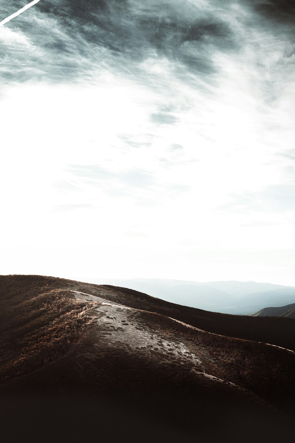 a person standing on top of a hill under a cloudy sky