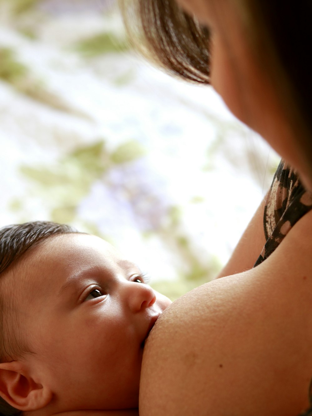woman breastfeeding baby during daytime