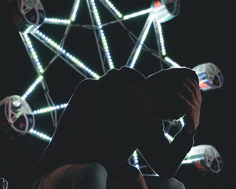 man sitting near Ferris wheel during night time