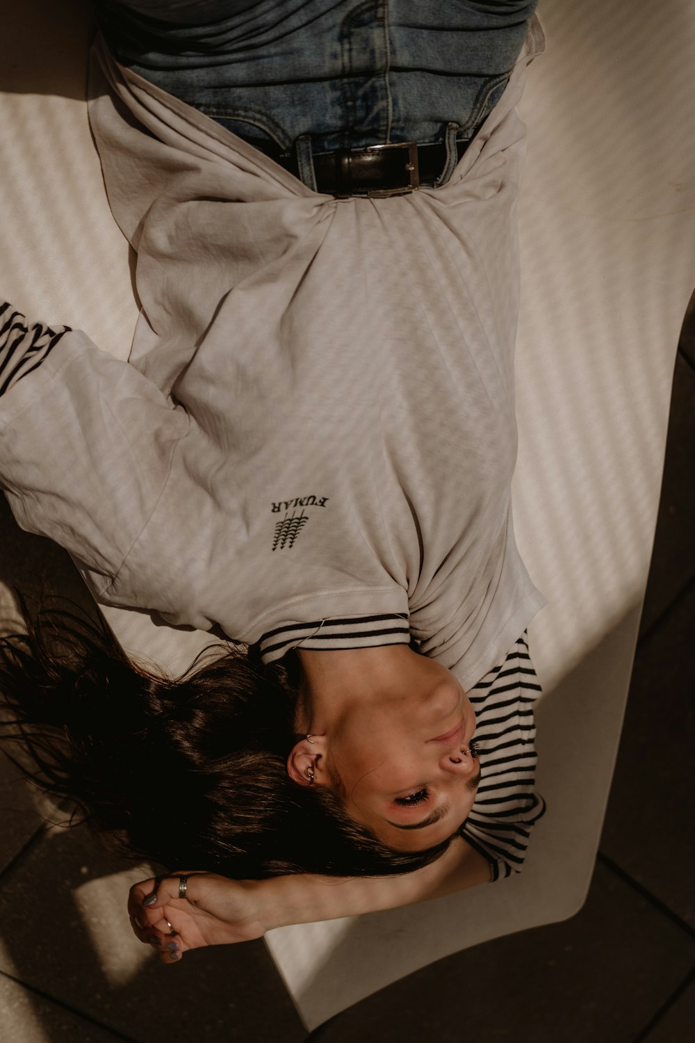 woman wearing gray shirt lying on white textile