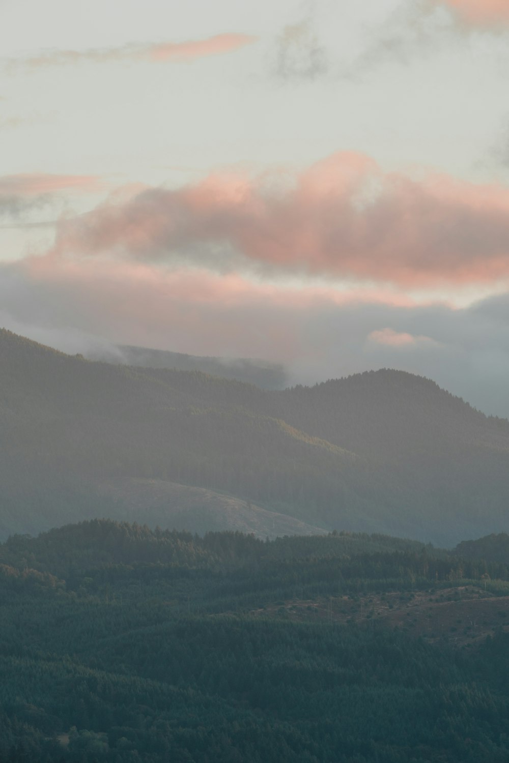 a view of a mountain range with a pink cloud in the sky