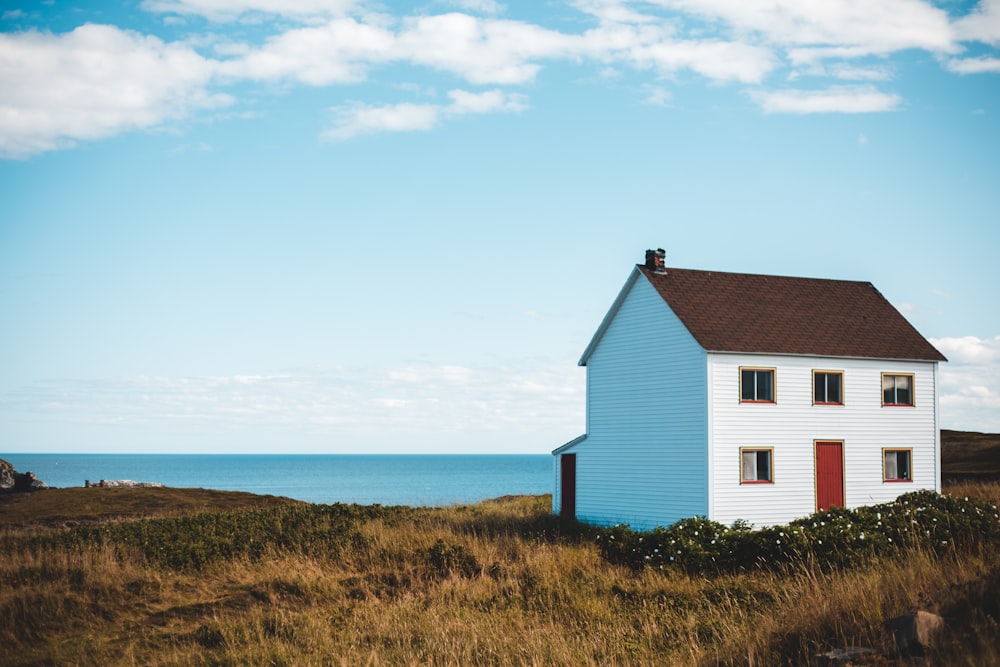 white and brown painted house in the middle of grass field