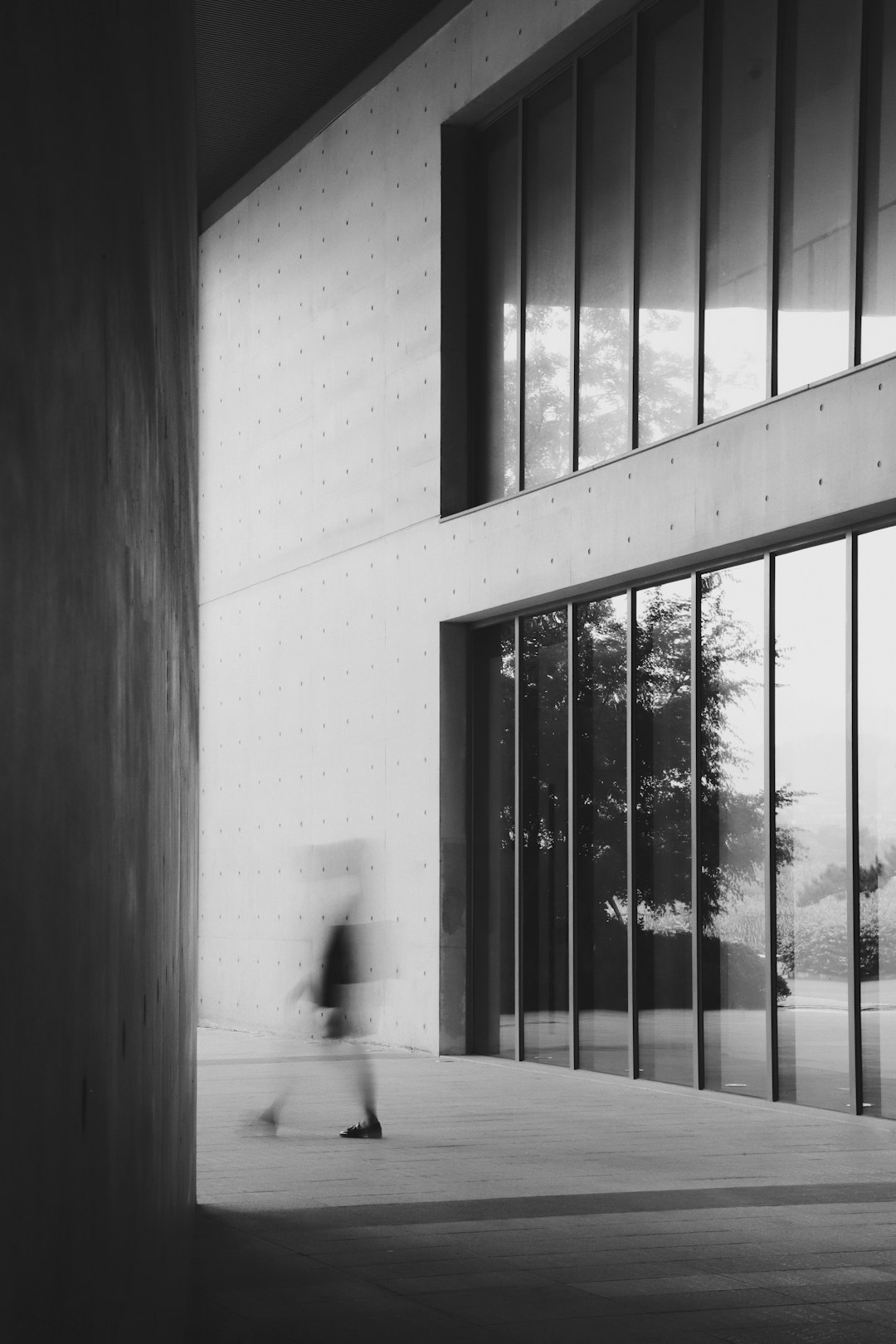 grayscale photography of person walking near wall