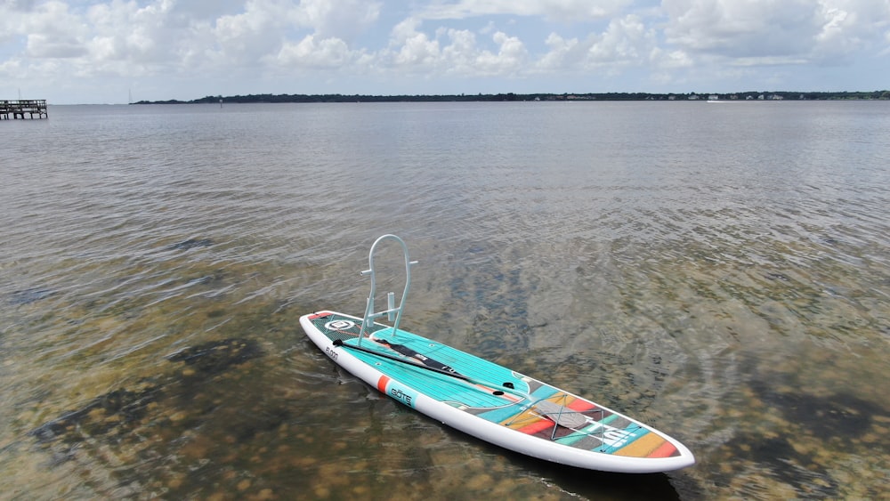 white and multicolored surfboard on body of water