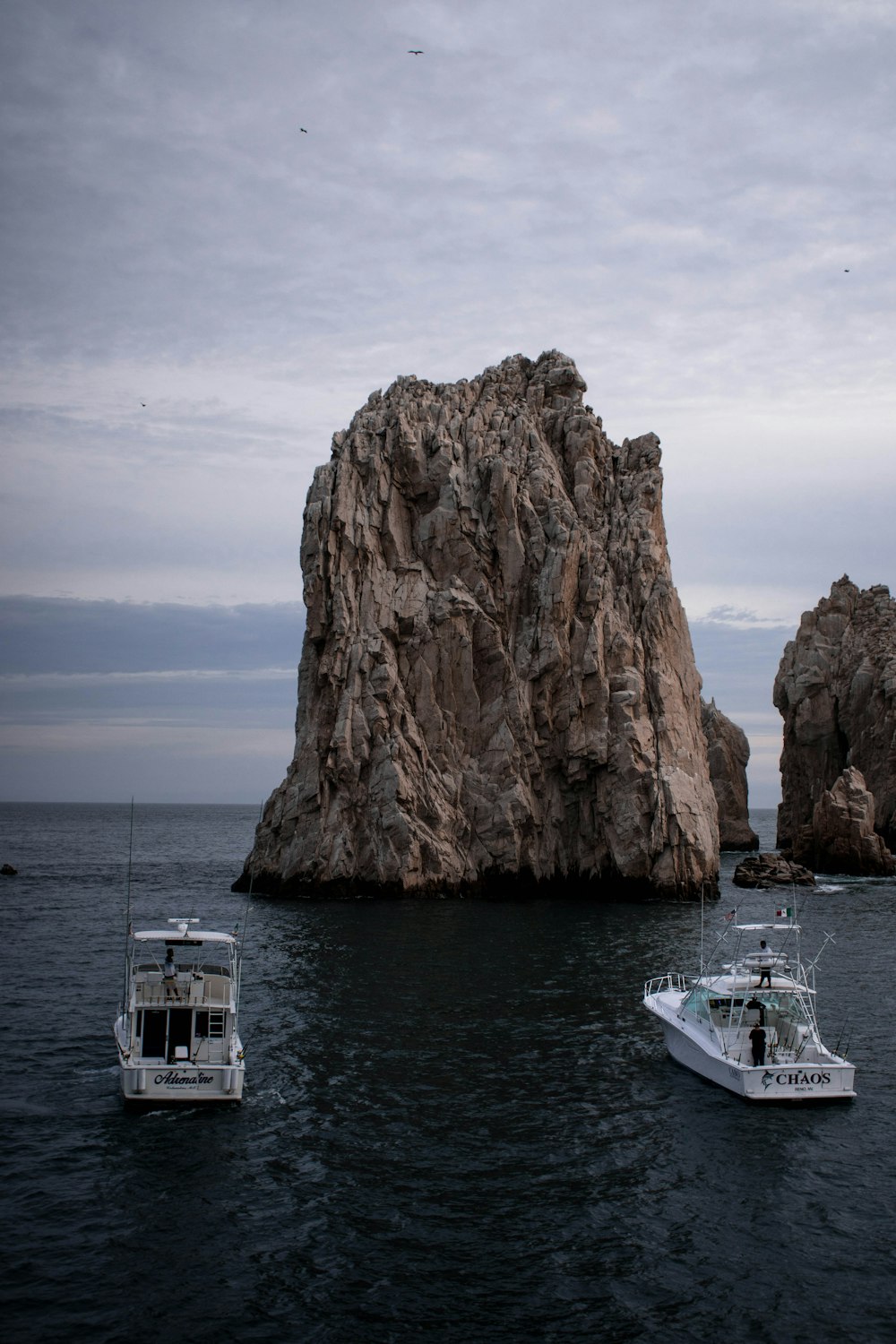 rock island with two boats in water