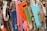 A stack of various flattened cardboard boxes and packaging is piled together. The boxes are of different sizes and colors, including bright orange, pink, blue, and green. Some have printed text and images, such as black bats on an orange background, indicating a Halloween theme.