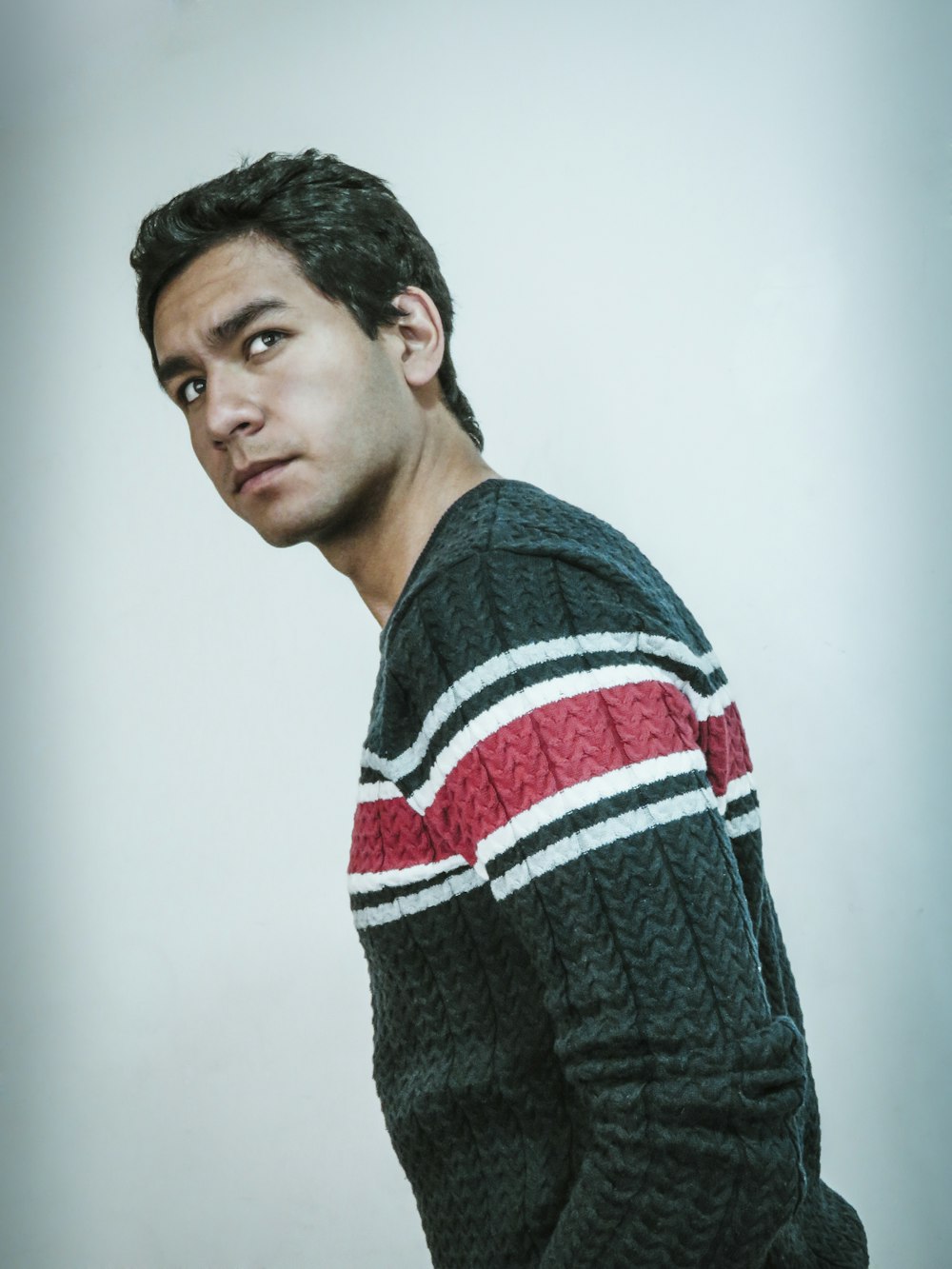 shallow focus photo of man in black, red, and white sweater