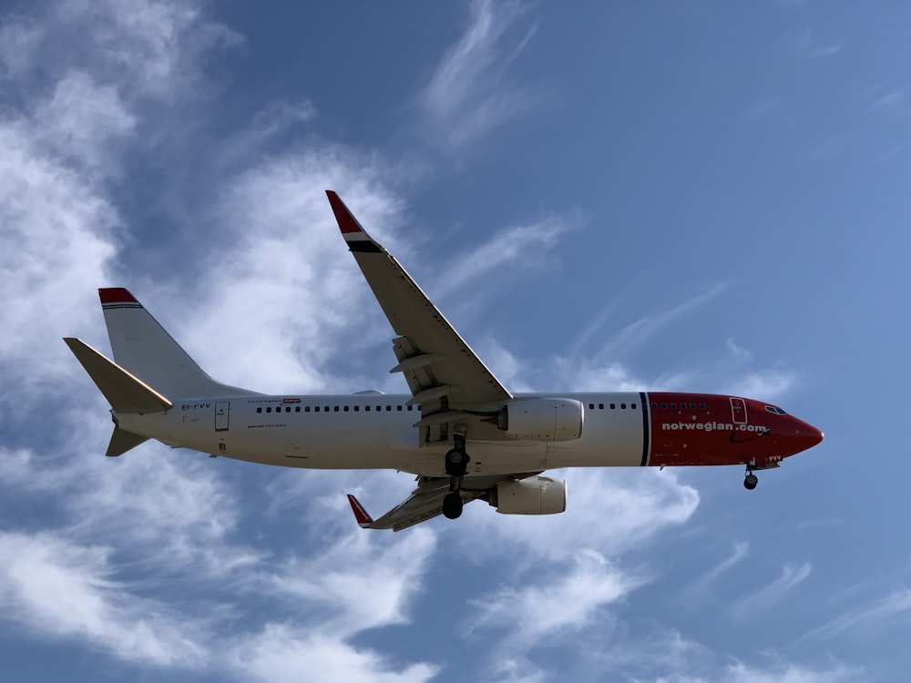 white and red airplane under blue and white skies